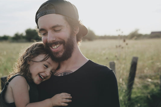 Papa portant sa fille dans ses bras, moment de tendresse pour la fête des pères 2026