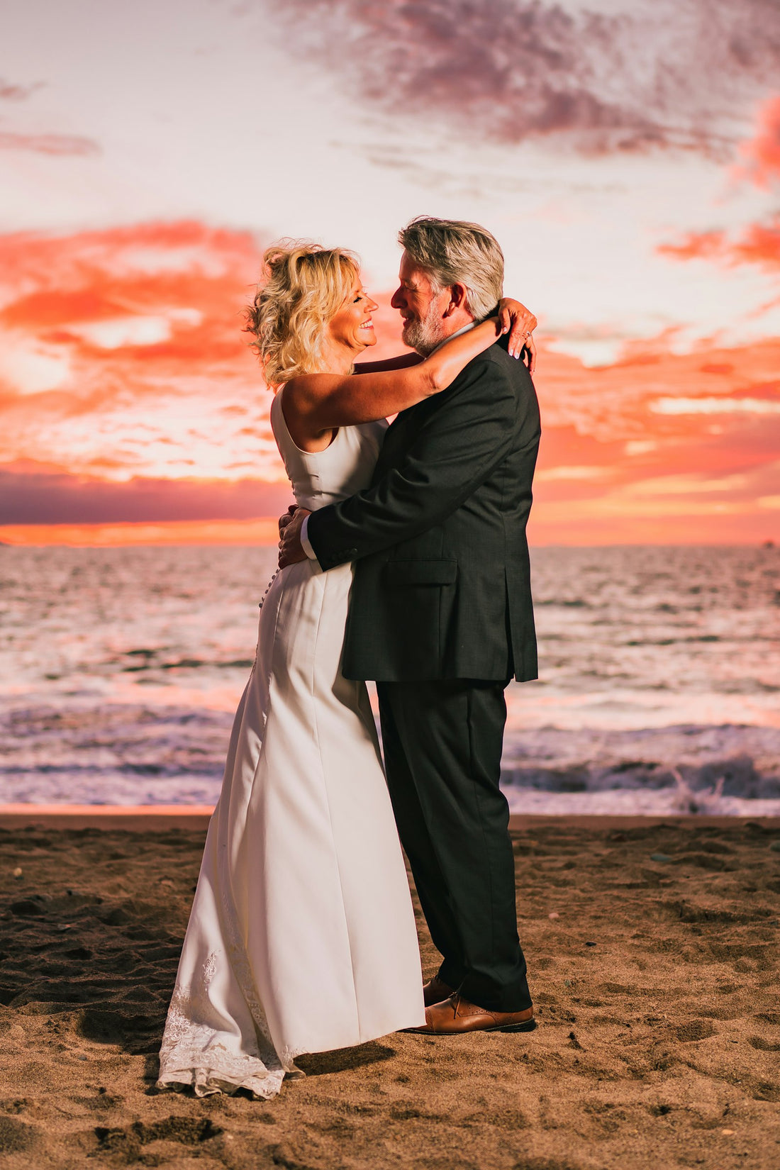Jeunes mariés s'embrassant sur la plage au coucher de soleil, cadeau noces de coton 1 an
